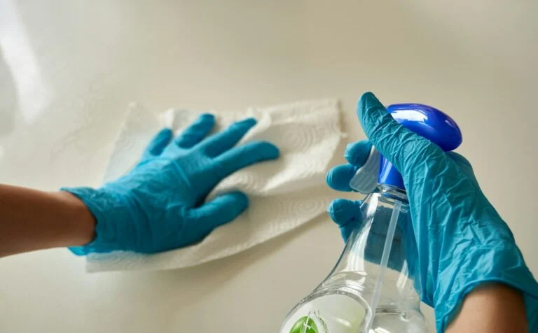 Gloved hands wiping and sanitising a surface